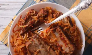 Pyszne żeberka w kapuście, duszona wieprzowina z warzywami, podane na talerzu z widelcem.