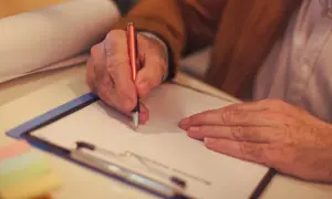 Mężczyzna pisze na papierze, przygotowując się do załatwienia spraw spadkowych bez testamentu.