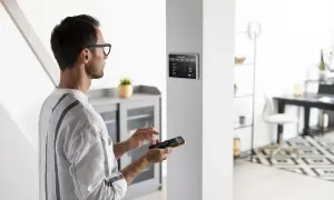 Un homme utilise une télécommande pour installer une alarme sur un écran tactile mural.