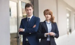 Para prawników w garniturach, stojących przed budynkiem.