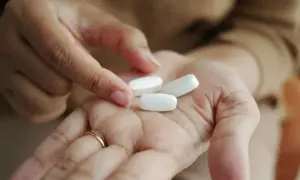 En hand håller tre vita tabletter, kanske för att visa sertralin 25 mg effekt.