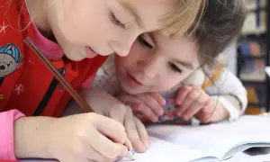 Zwei Kinder lernen gemeinsam an einer Lerntheke Methode, konzentriert auf ihr Heft.