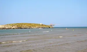 La chianca di Vieste, con la sua struttura in legno sul mare, si staglia contro il cielo azzurro. L'acqua cristallina invita a un bagno rinfrescante.