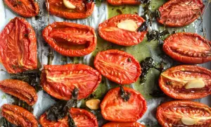 Tomates au four, coupées en deux, rôties avec de l'ail et des herbes, leur chair concentrée et savoureuse.