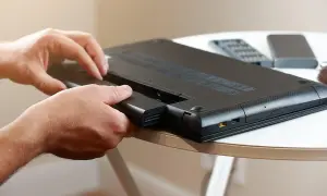 Dłonie wyjmują baterię z laptopa. To pierwszy krok, by sprawdzić stan baterii w laptopie i zadbać o jego wydajność.