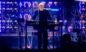 Hans Zimmer w Krakowie, na tle świecącej ściany syntezatorów i kabli, tworzy magiczną atmosferę.