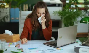 Kobieta z katarem pracuje przy biurku, zastanawiając się, czy na umowie zlecenie jest L4.