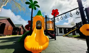 Kolorowy plac zabaw z zjeżdżalnią i drabinkami, obok drewniane domki nad morzem Dziedzic.