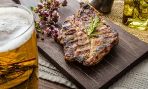Succulenta grigliata con rosmarino, accompagnata da una birra dorata e fiori di origano.