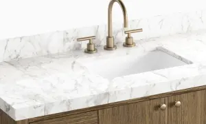 A modern bathroom vanity with a white sink, brass faucet, and a white marble countertop. This image showcases a stylish option to replace bathroom countertop.