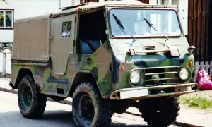 En kamouflerad Volvo L3314 står parkerad framför ett hus.