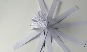 Papierowa ozdoba choinkowa 3D w trakcie tworzenia, z pasków z geometrycznym wzorem.