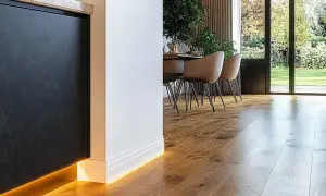 Nowoczesne wnętrze z drewnianą podłogą i oświetleniem LED. Eleganckie rozwiązanie co zamiast listwy progowej, tworzy subtelny efekt.
