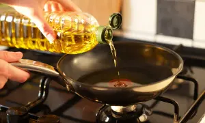 Mano versa olio in padella sul fornello, pronto per friggere.