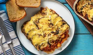 Une part généreuse de moussaka végétarienne, gratinée au fromage, servie avec du pain grillé. Un plat réconfortant et savoureux.