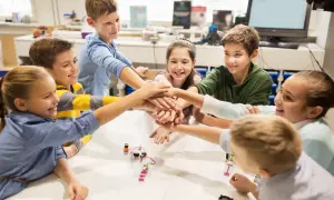 Kinder legen ihre Hände in der Mitte zusammen, ein Zeichen für Teamwork in ihrem mint kita-Projekt.
