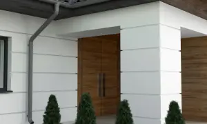 Nowoczesny dom z białym tynkiem i drewnianymi elementami. Eleganckie boniowanie elewacji podkreśla architekturę.