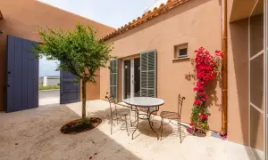 Un patio andaluz con mesa y sillas de hierro forjado, un árbol frutal y buganvillas. Ideas para un oasis mediterráneo.