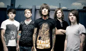 Bring Me The Horizon członkowie, z tatuażami i kolczykami, pozują przed ciemnym tłem.
