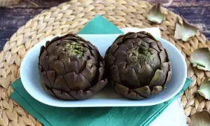 Deux artichauts violets sur une assiette blanche, prêts pour une recette d'artichaut savoureuse.