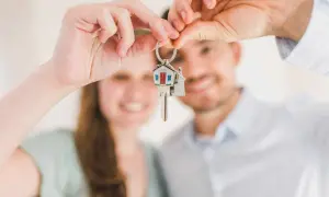 Coppia felice mostra le chiavi di casa, un promemoria delle 10 cose da sapere prima di comprare casa.