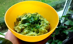 Pyszne guacamole co to? Zielona pasta z awokado, doprawiona świeżą kolendrą, w żółtej miseczce.