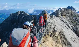 Drei Wanderer auf einer Hängebrücke während einer 5-tägigen Alpenwanderung. Die Aussicht ist atemberaubend.