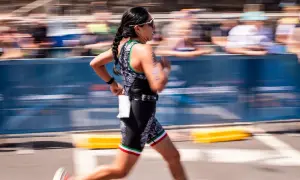 A woman in a triathlon suit, her hair in braids, runs with determination. This is the essence of Ironman training.