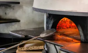 Piec do pizzy z palącym się ogniem i łopatą do pizzy.