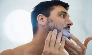 La cara de hombre con espuma de afeitar, preparándose para un afeitado apurado.