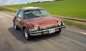En brun AMC Pacer SC kör på en landsväg, med gröna fält som sträcker sig längs vägen.