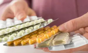 Hände halten mehrere Blisterpackungen mit Tabletten und Kapseln. Die Frage, darf man Tabletten mit ins Flugzeug nehmen, wird hier visuell thematisiert.