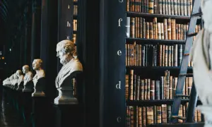 Rzędy popiersi i zabytkowych ksiąg w bibliotece, gdzie mimetyzm w literaturze odzwierciedla się w dążeniu do wiernego przedstawienia rzeczywistości.