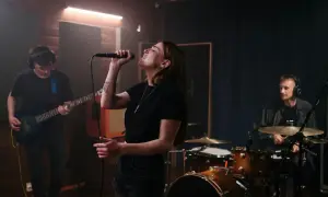 Wokalistka śpiewa do mikrofonu, gitarzysta gra na basie, a perkusista wybija rytm. Co to za melodia?