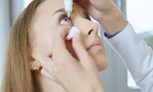Krople na ciśnienie w oku podawane przez lekarza. Delikatna aplikacja leku.