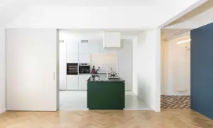 Moderna cucina verde in un ampio soggiorno open space. Pavimenti in parquet e resina, elettrodomestici a scomparsa.