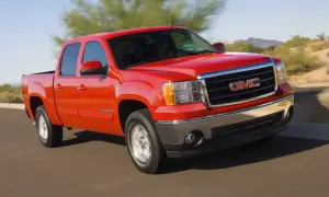 Czerwony pickup GMC Sierra z napędem 4x4 jedzie po pustynnej drodze.