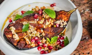 Gebackene Aubergine mit Tahini, Granatapfelkernen und Minze. Ein köstliches Gericht, das zeigt, wie vielseitig auberginen rezepte im backofen sein können.