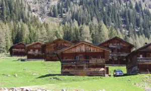 Holzhäuser im Villgratental, umgeben von grünen Wiesen und Nadelwäldern. Eine Karte des Villgratentals würde diese idyllische Landschaft zeigen.