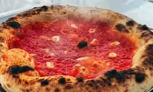 Eine dampfende Pizza Marinara mit knusprigem Rand und roten Tomaten.