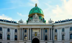 Prunkvolle Kuppel des Hofburg-Palastes in Wien, ein absolutes Wien must see. Majestätische Architektur unter blauem Himmel.