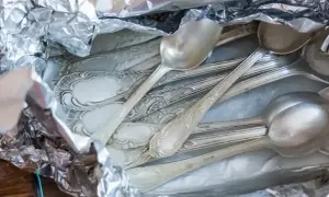 Stare, ozdobne łyżki i widelce owinięte w folię aluminiową, gotowe do czyszczenia srebra.