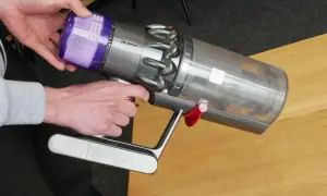 Ręce wyjmujące fioletowy filtr z odkurzacza Dyson.