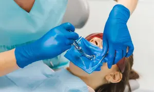 Dentysta zakłada koferdam, izolując pole zabiegowe.
