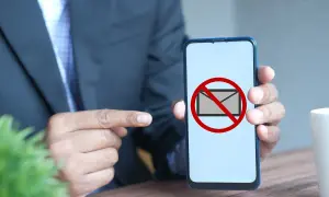 Hombre señala un teléfono con un símbolo de "no" sobre un sobre. Parece que no me llegan los sms.