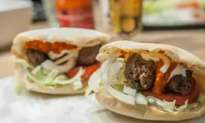 Två saftiga cevapcici i pitabröd med lök, tomat och sås. Perfekt för en snabb och god måltid, som ett enkelt cevapcici recept.