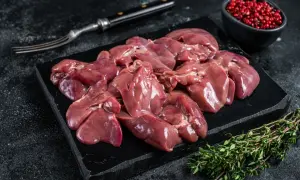 Frische barf innereien, roh und appetitlich auf einem schwarzen Brett, garniert mit Thymian und rosa Pfeffer.