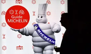 El muñeco Michelin, con su banda "MICHELIN", posa junto a un hombre con copa. Un símbolo de los restaurantes con estrella Michelin.