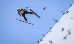 Skoczek narciarski w locie, a obok niego dron. Zastanawiasz się, ile ważą narty do skoków narciarskich?