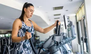 Frau trainiert auf einem Crosstrainer, um ihren Kalorienverbrauch zu steigern.